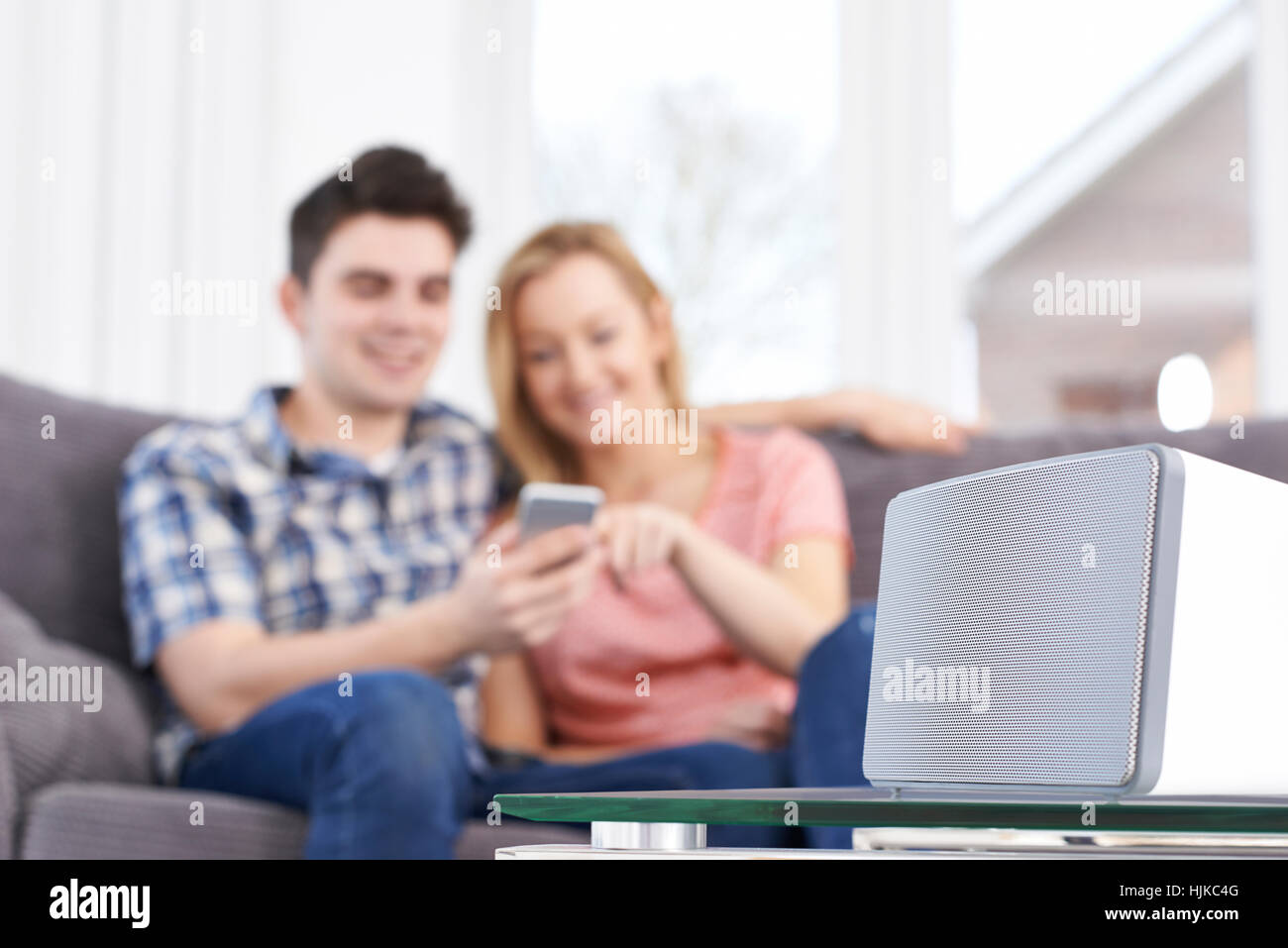 Giovane lo streaming di musica dal telefono cellulare per altoparlante senza fili Foto Stock