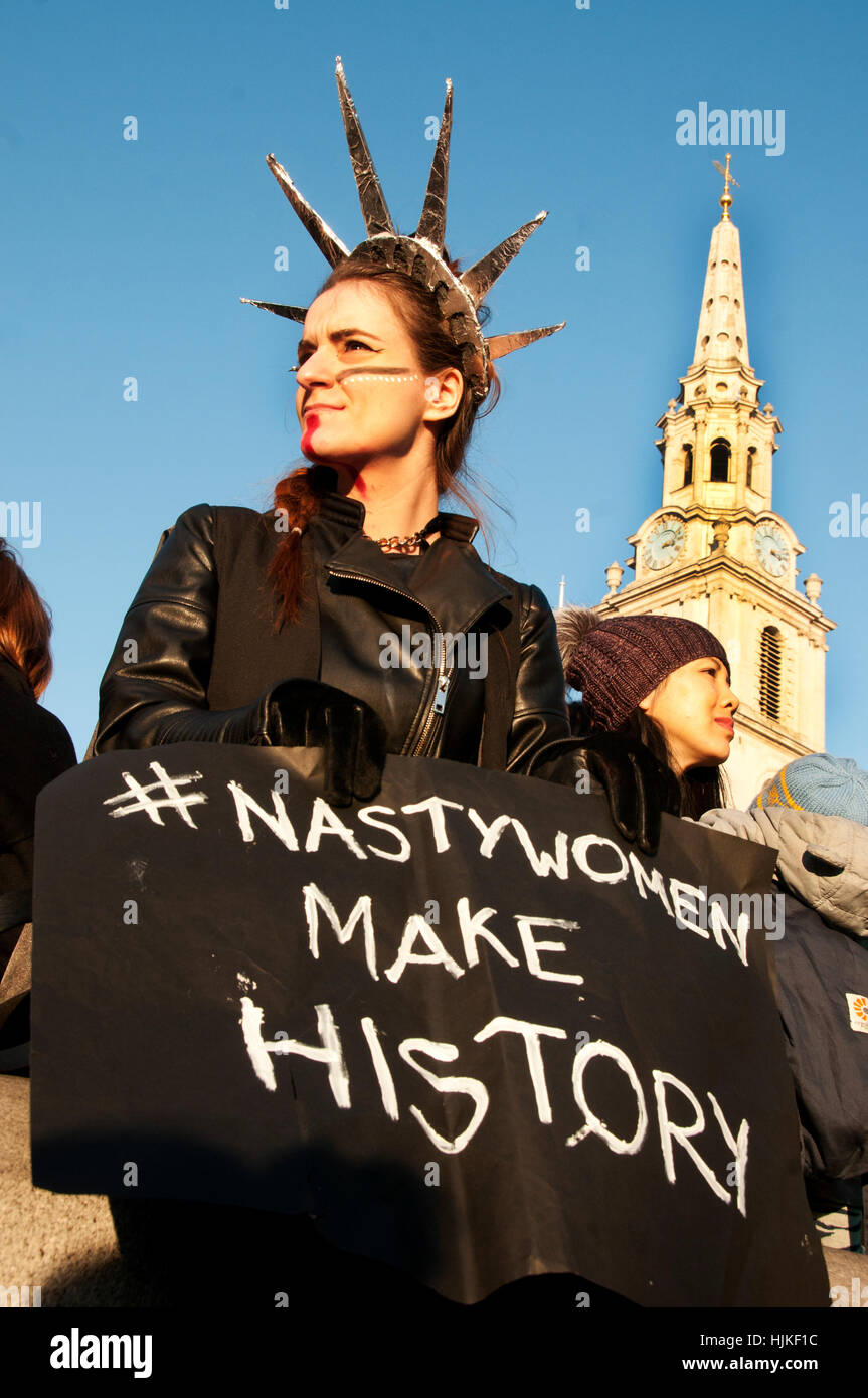 Le donne del marzo contro Trump. Una donna con un battuto di fronte indossa una statua della Libertà copricapo e detiene un brutto donne banner Foto Stock