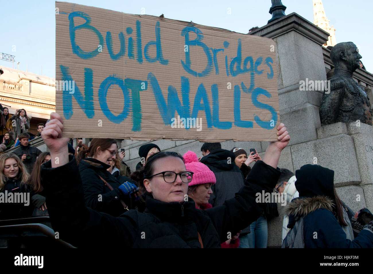 Le donne di anti-Trump marzo, Londra. Una donna in Trafalgar Square detiene un cartello che dice "costruire ponti e non muri". Foto Stock