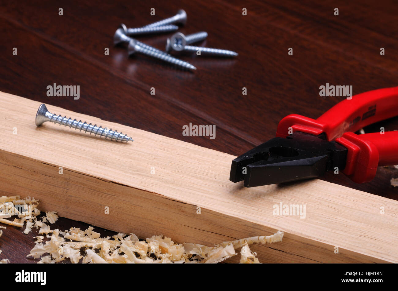 Trucioli di legno, rosso mattone e pinza su uno sfondo scuro Foto Stock