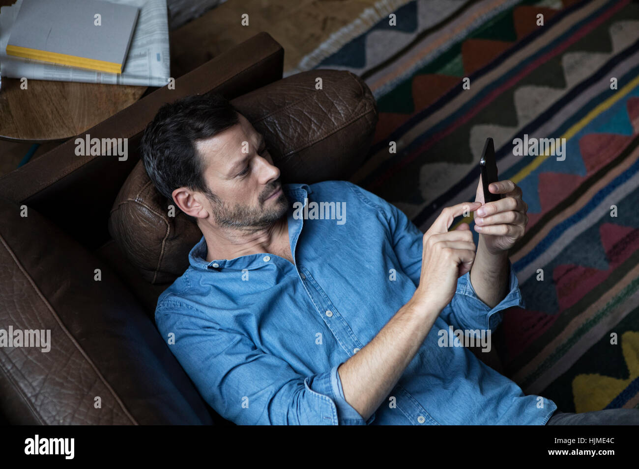 Uomo disteso sul lettino, utilizzando smart phone Foto Stock