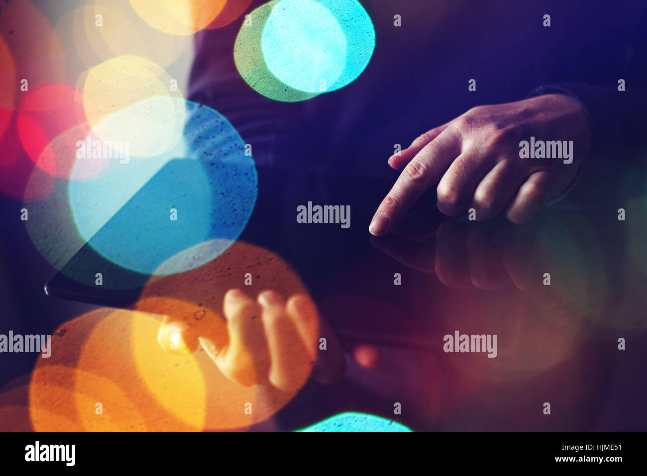Close up di mani femminili tramite digital computer tablet, abstract low key con composizione colorata luce bokeh di fondo Foto Stock