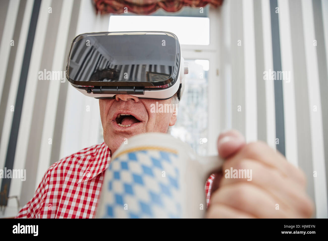 Senior uomo azienda boccale di birra indossando occhiali VR Foto Stock