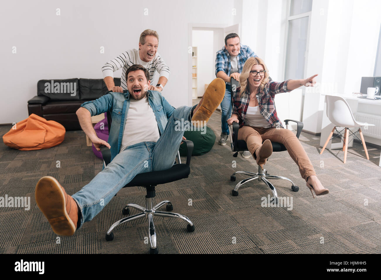 Positivo uomini allegra spingendo le sedie da ufficio Foto Stock