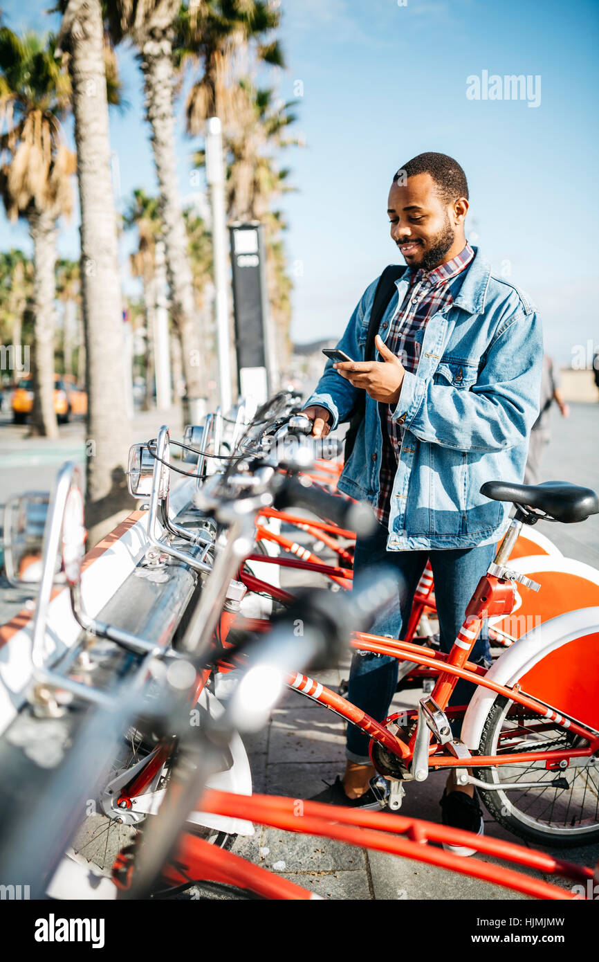 Spagna, Barcellona, giovane uomo con lo smartphone affittare una bici da città Foto Stock