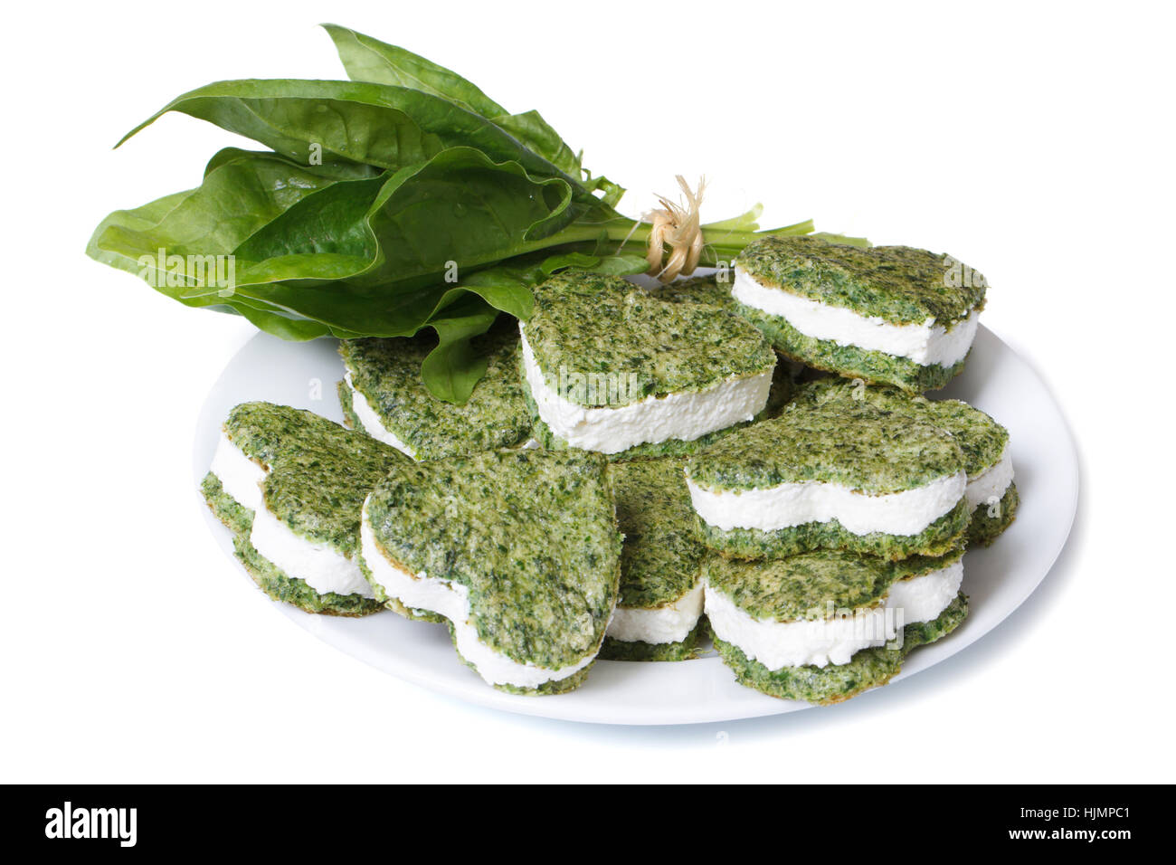 Pasticceria cuore verde con crema di formaggio e un mazzetto di spinaci freschi isolati su sfondo bianco Foto Stock