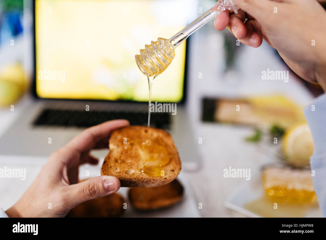 La donna il gocciolamento del miele per toast a casa, close-up Foto Stock