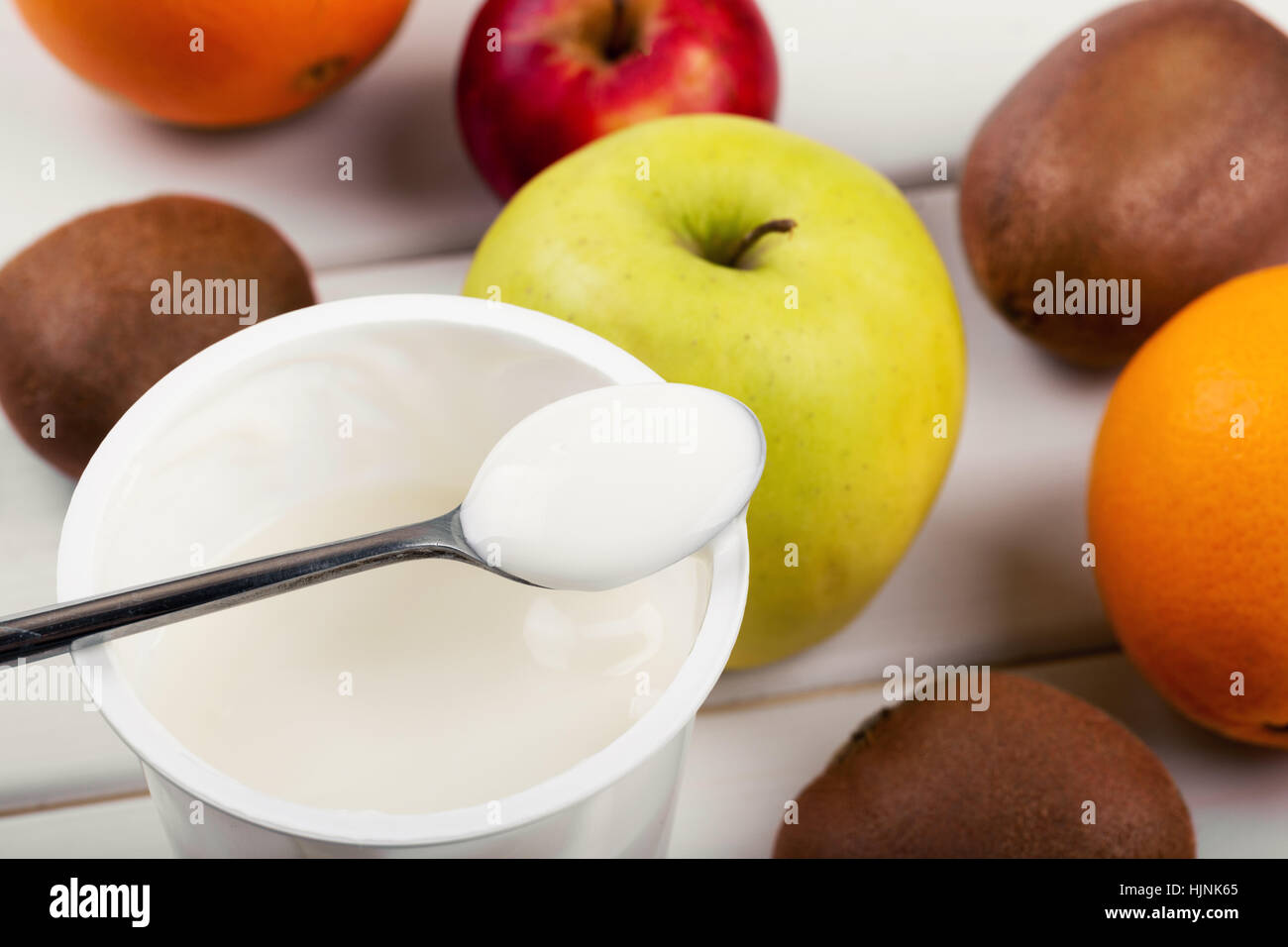 Cucchiaio con yogurt e frutta su bianco tavolo in legno Foto Stock