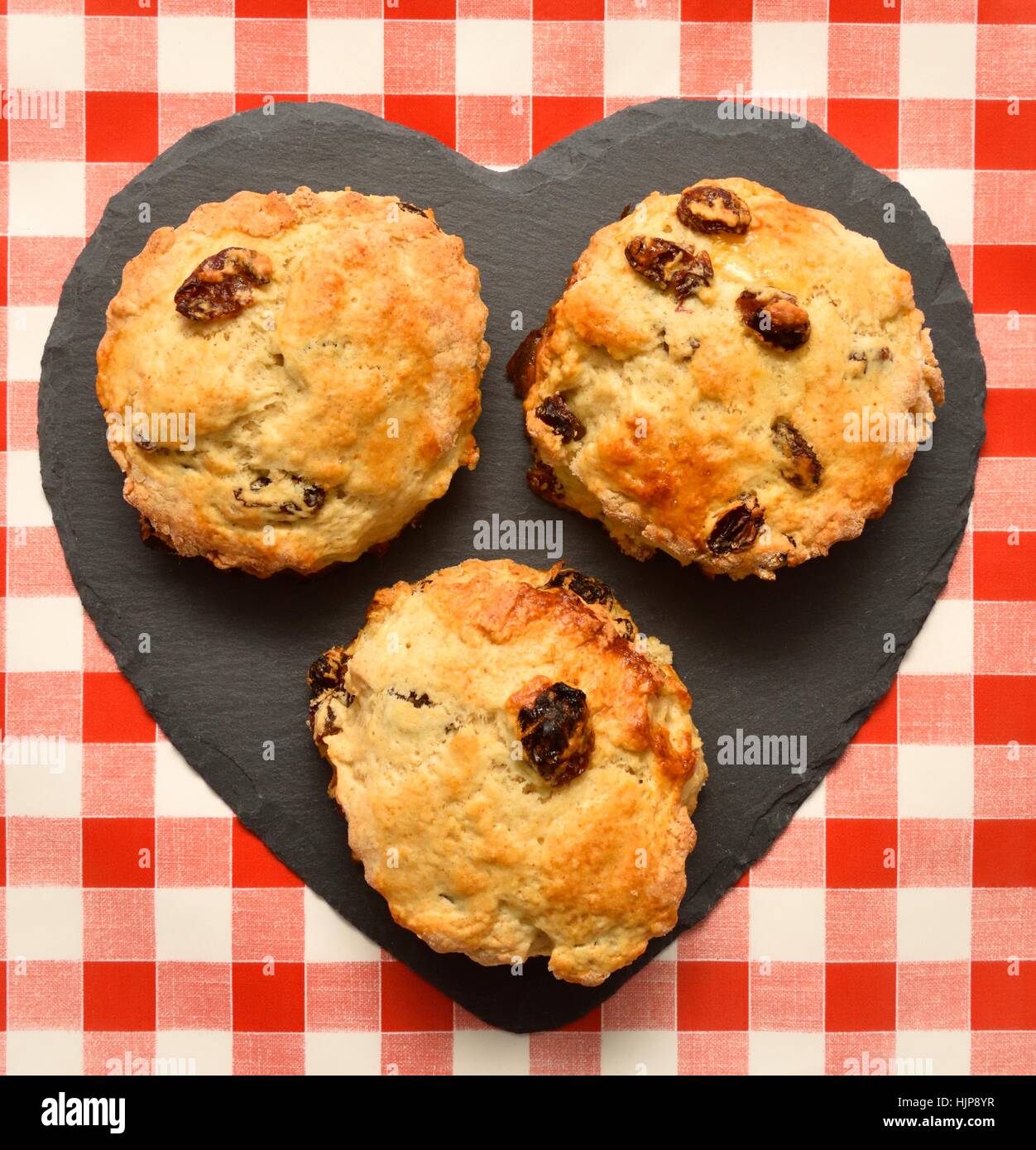 3 scones su un cuore pezzo sagomato di ardesia. Foto Stock