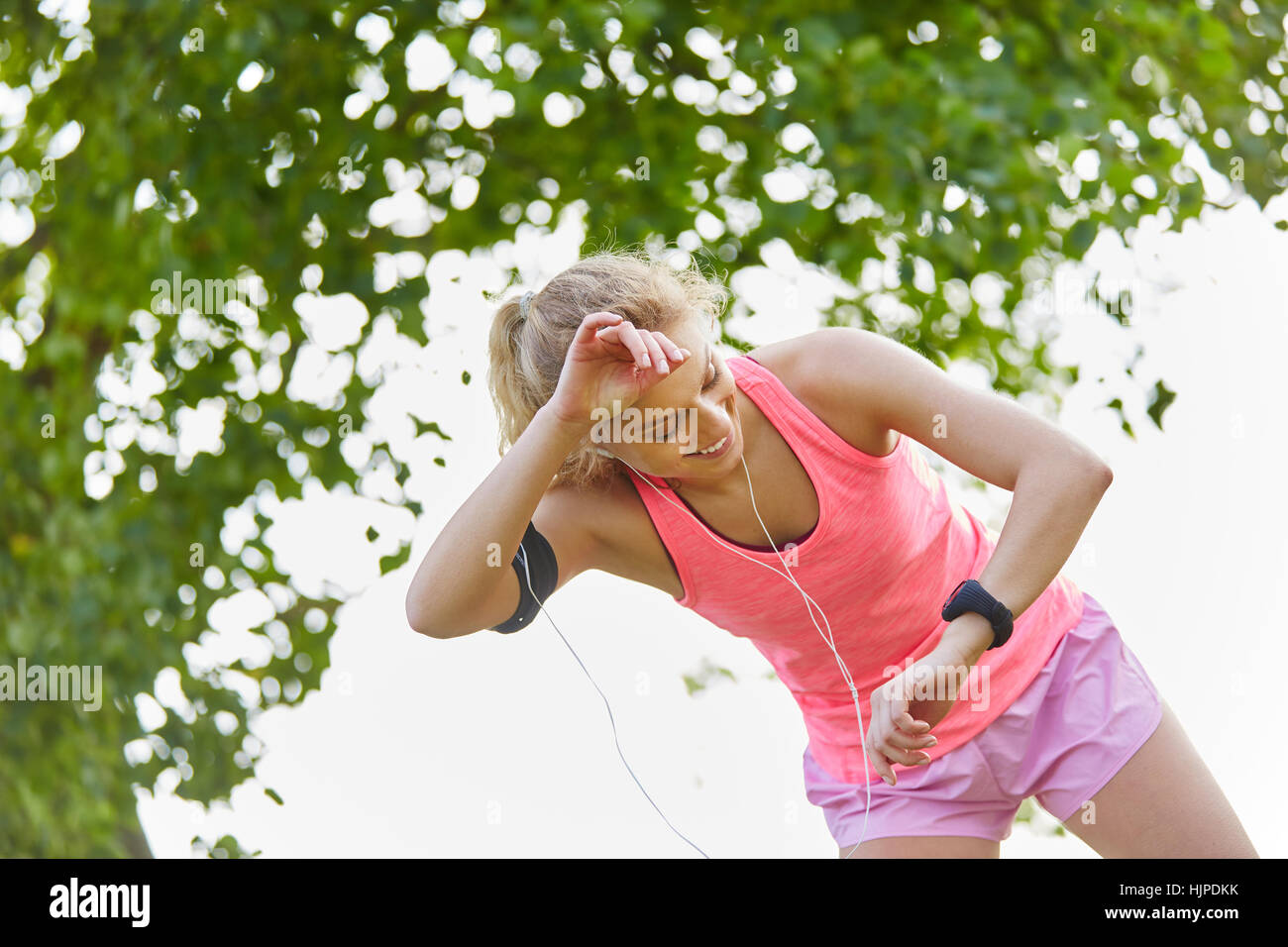 Esaurito donna guarda a smartphone dopo allenamento controllando i suoi segni vitali Foto Stock