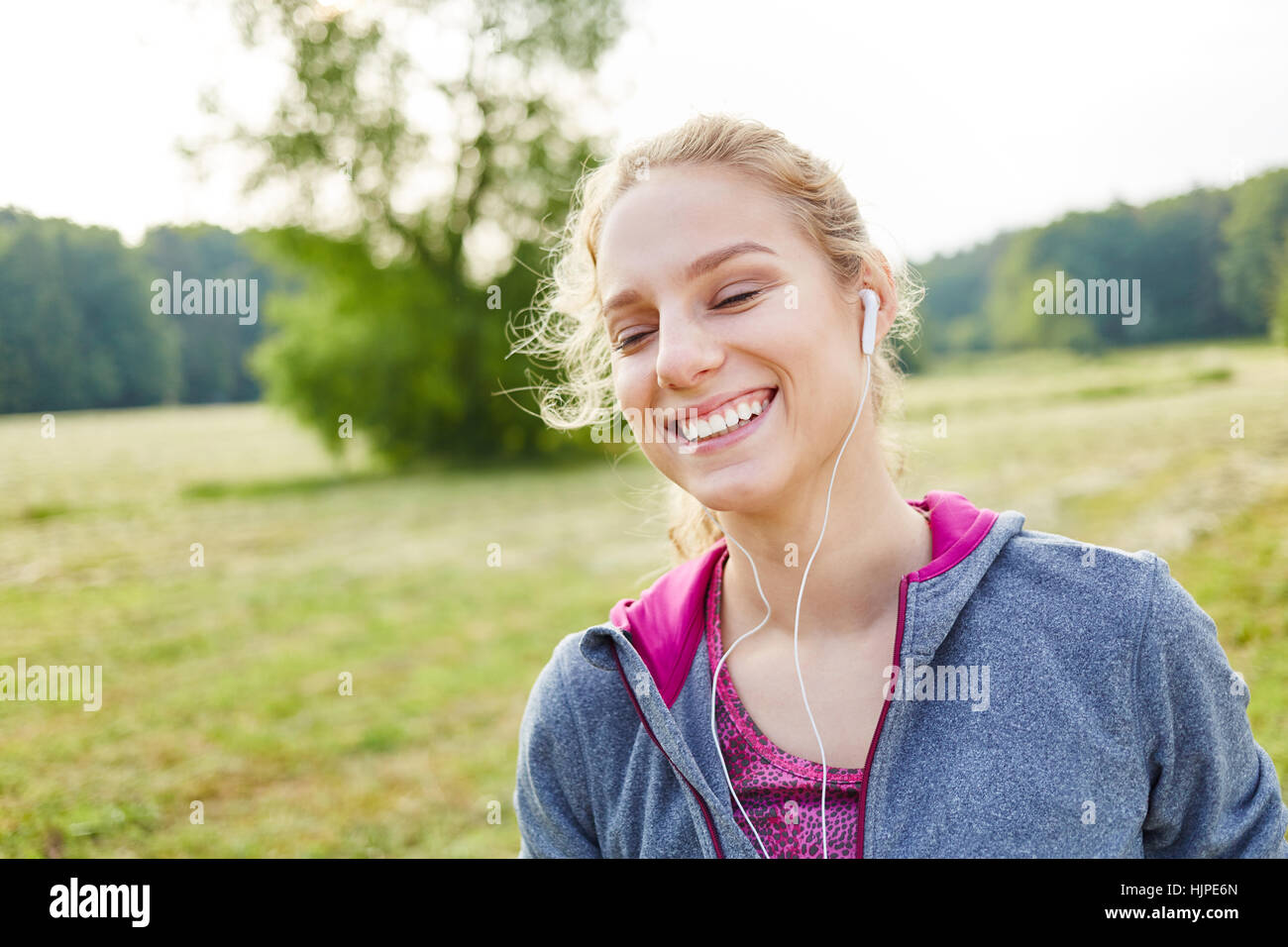 Giovane donna al parco ascoltando musica con gioia Foto Stock