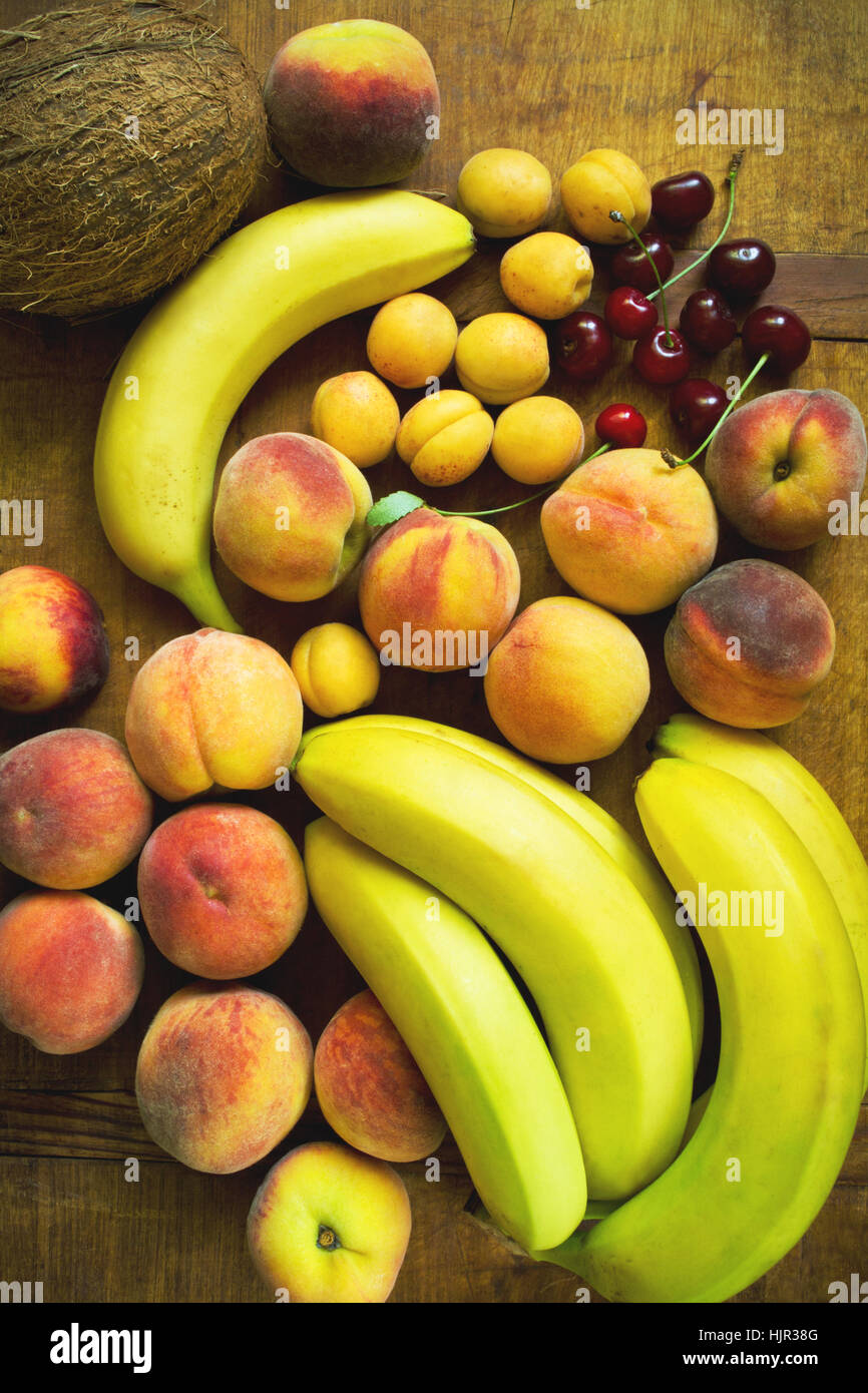 Frutta fresca assortimento con banane, pesche, albicocche, noce di cocco e ciliegia, vista dall'alto Foto Stock