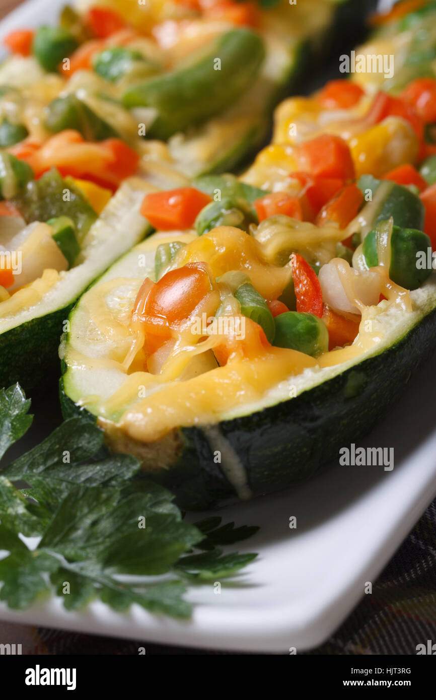 Cibo vegetariano: cotto zucchine ripiene di verdure su una piastra bianca macro. verticale. Foto Stock