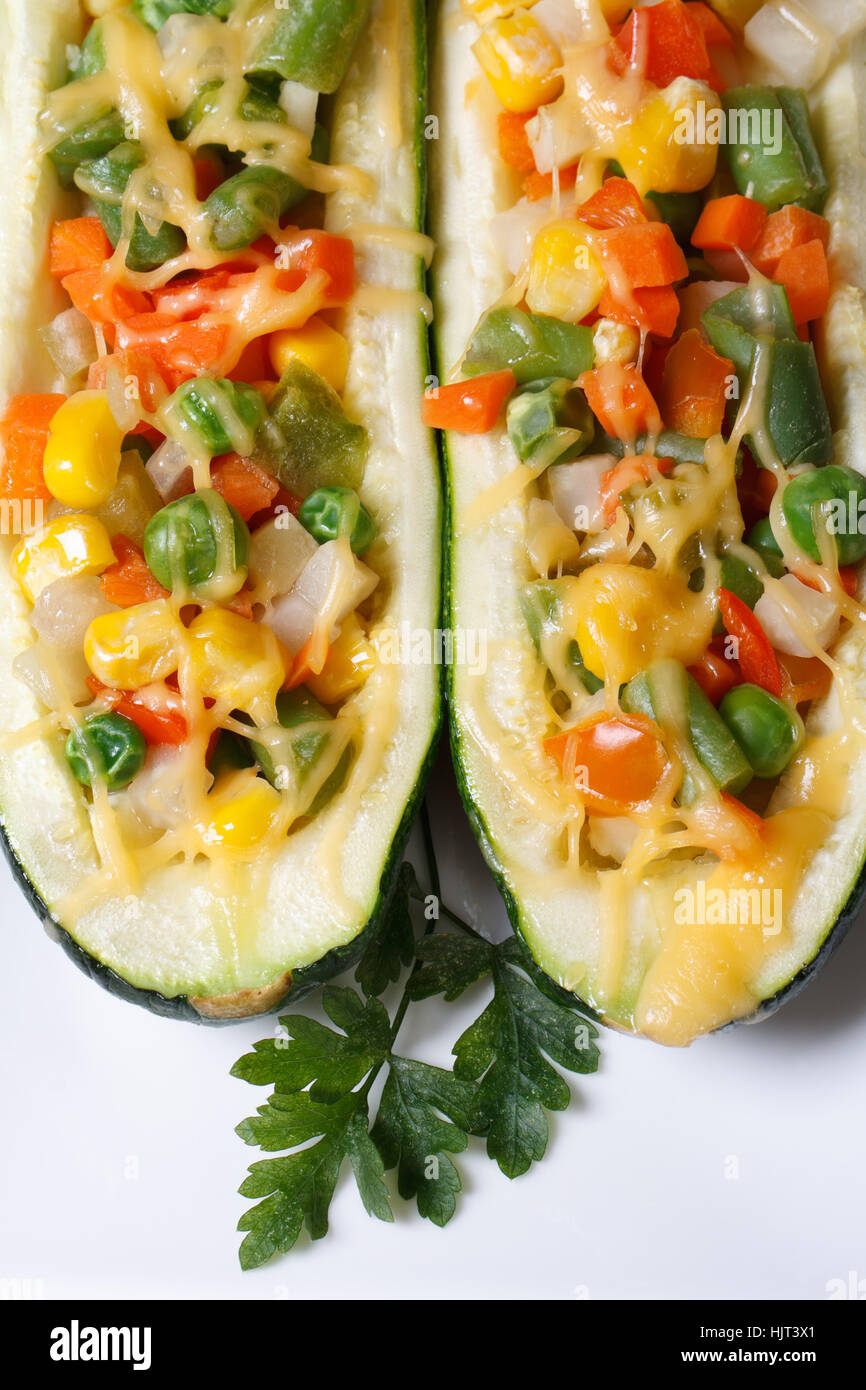 Cibo vegetariano: cotto zucchine ripiene di verdure closeup su una piastra bianca. vista verticale da sopra Foto Stock