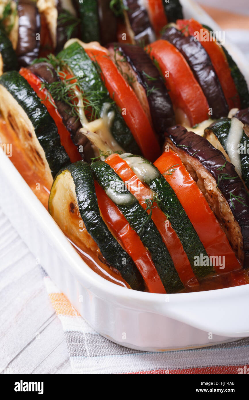 Melanzane, zucchine e pomodori al forno con formaggio ed erbe closeup verticale Foto Stock