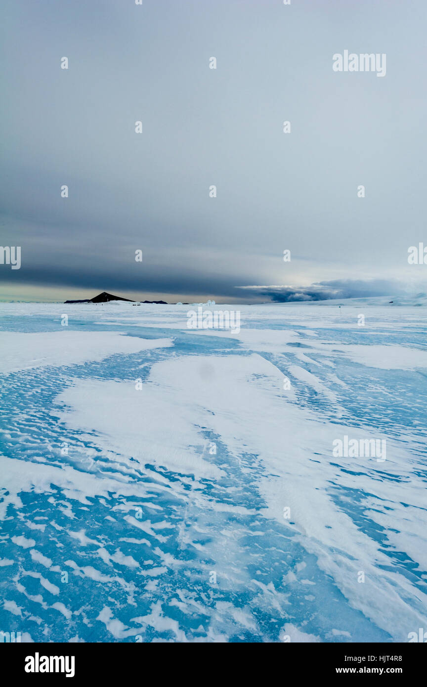 Modelli di vento si radunano in derive di neve sul mare ghiacciato di ghiaccio in Antartide. Foto Stock