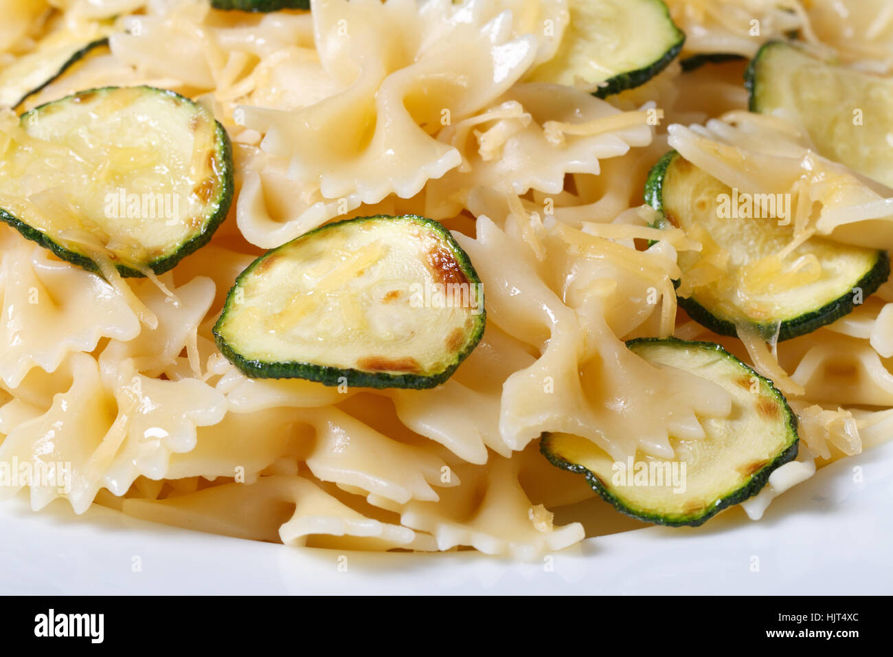 Farfalle di pasta con zucchine e formaggio su una piastra bianca orizzontale macro Foto Stock