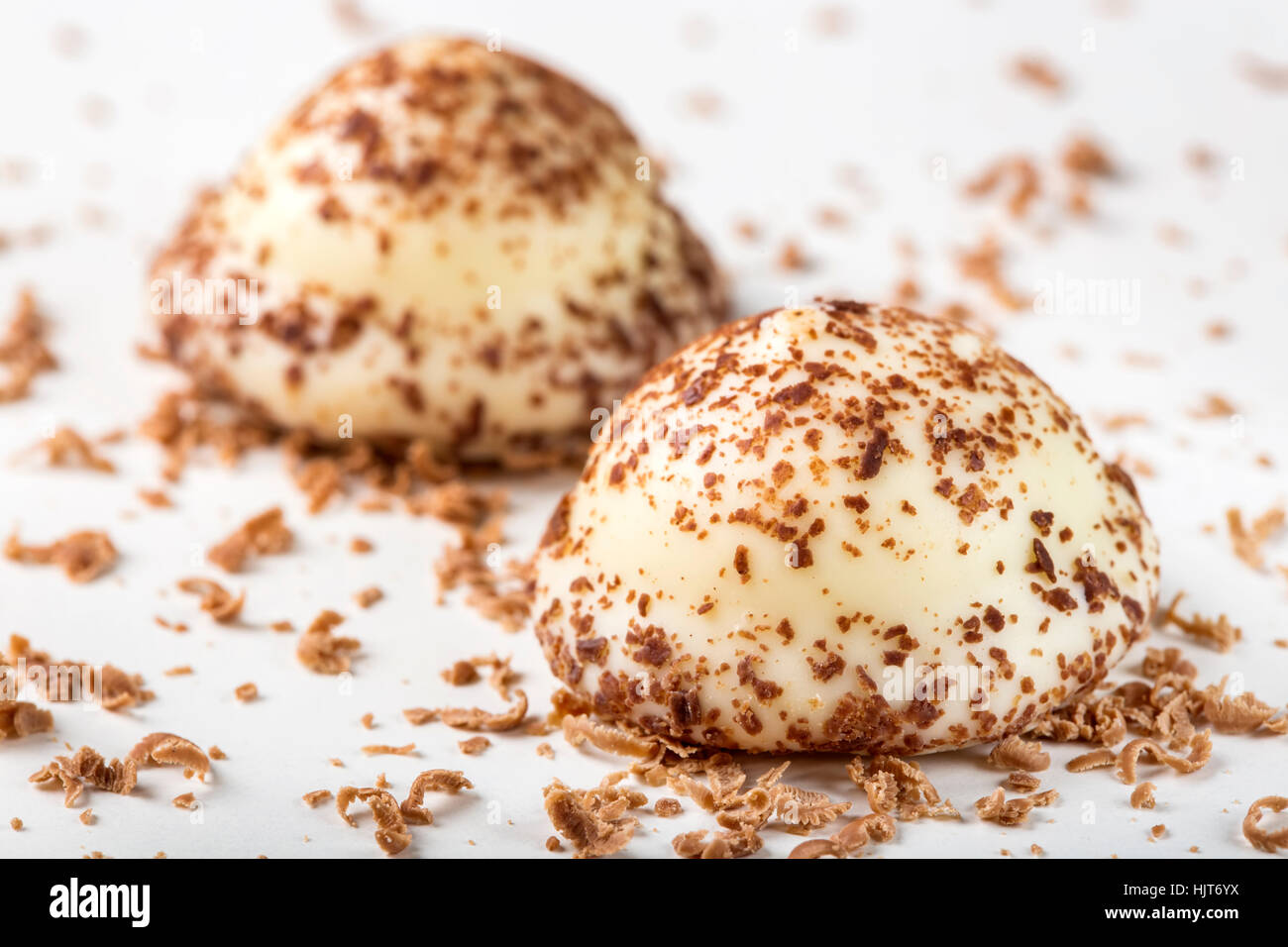 Due vaniglia pearl caramelle e cioccolato fondente grattugiato su sfondo bianco Foto Stock
