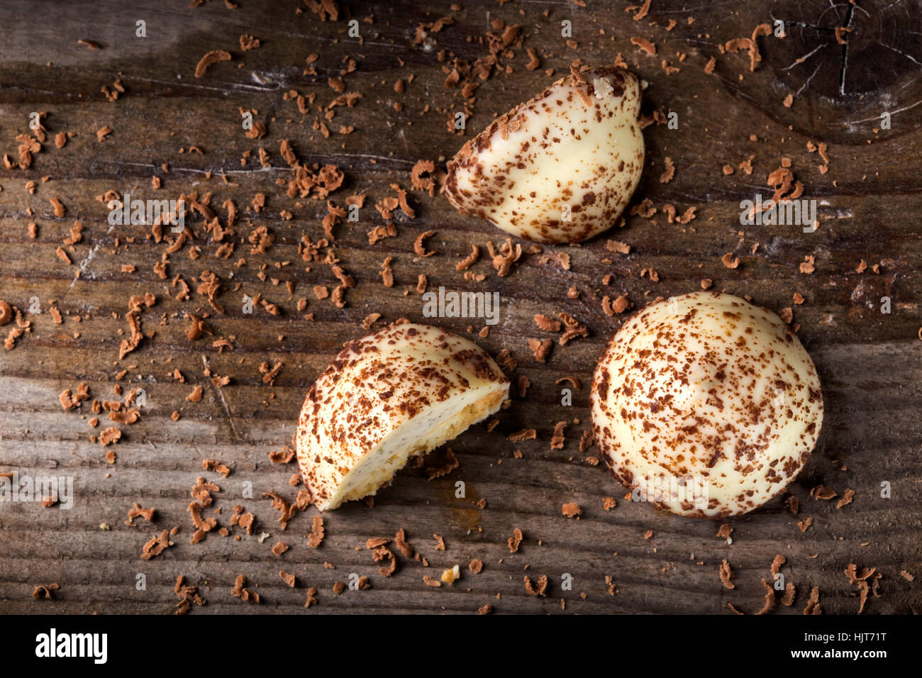 Due vaniglia Candy Pearl, uno tagliato a metà e cioccolato fondente grattugiato su sfondo di legno Foto Stock