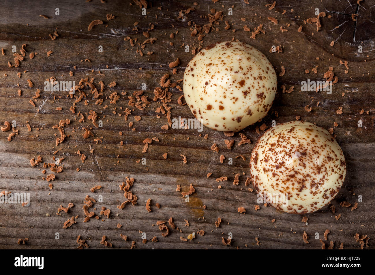 Due vaniglia pearl caramelle e cioccolato fondente grattugiato su sfondo di legno Foto Stock