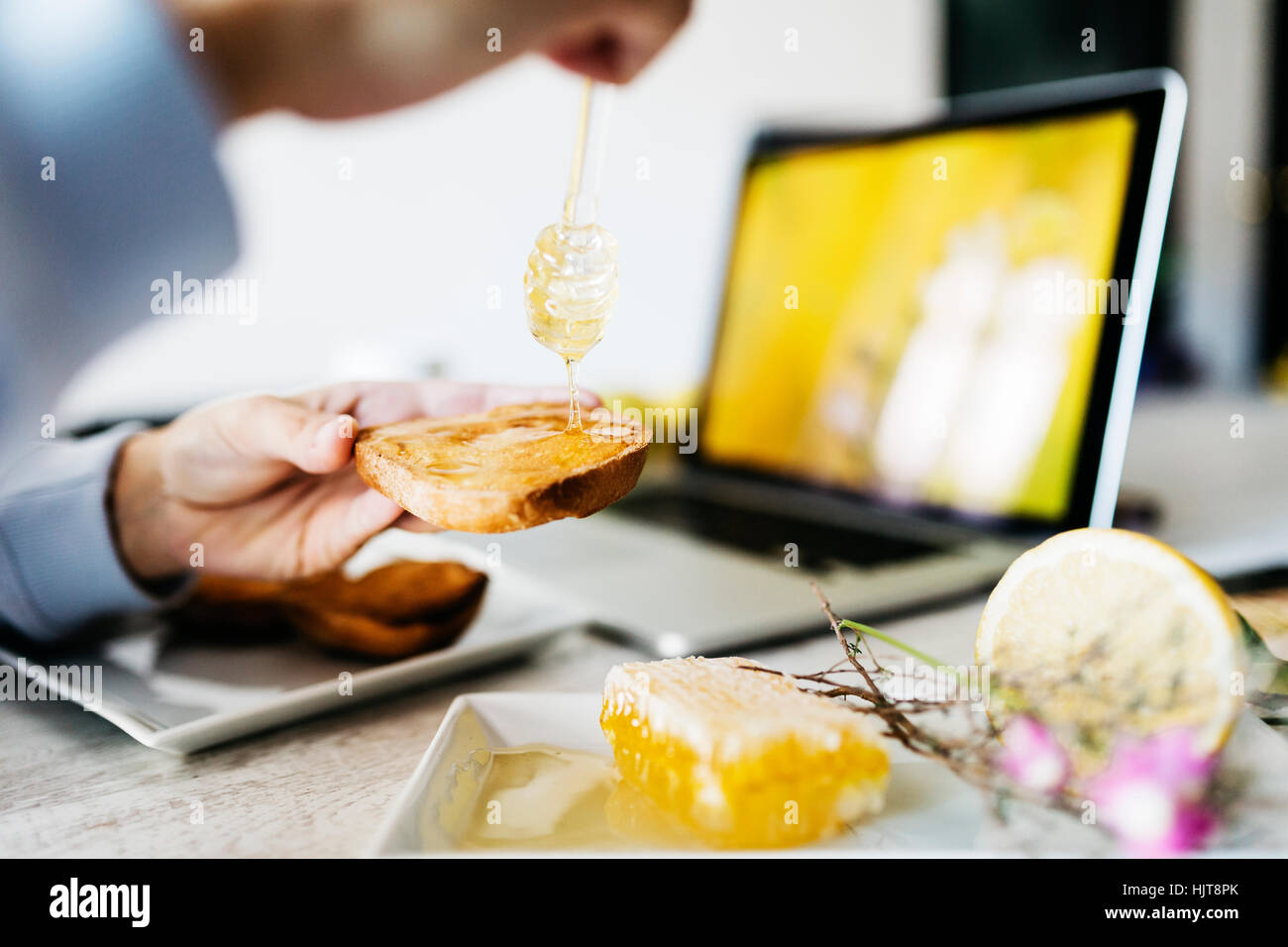 La donna il gocciolamento del miele per toast al suo luogo di lavoro, close-up Foto Stock
