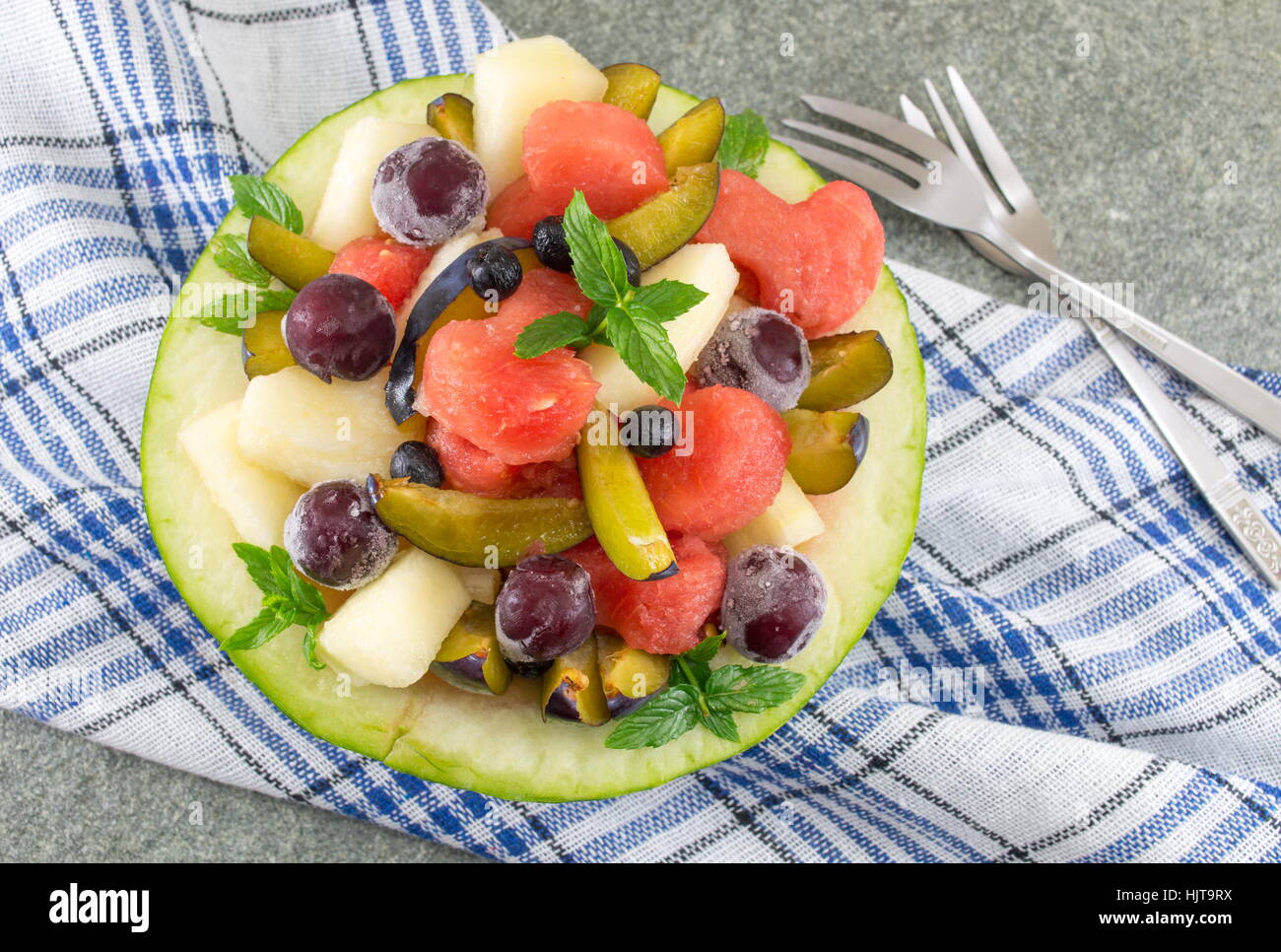 Macedonia di frutta fresca servita in un melone con heartshaped watermellon fette Foto Stock