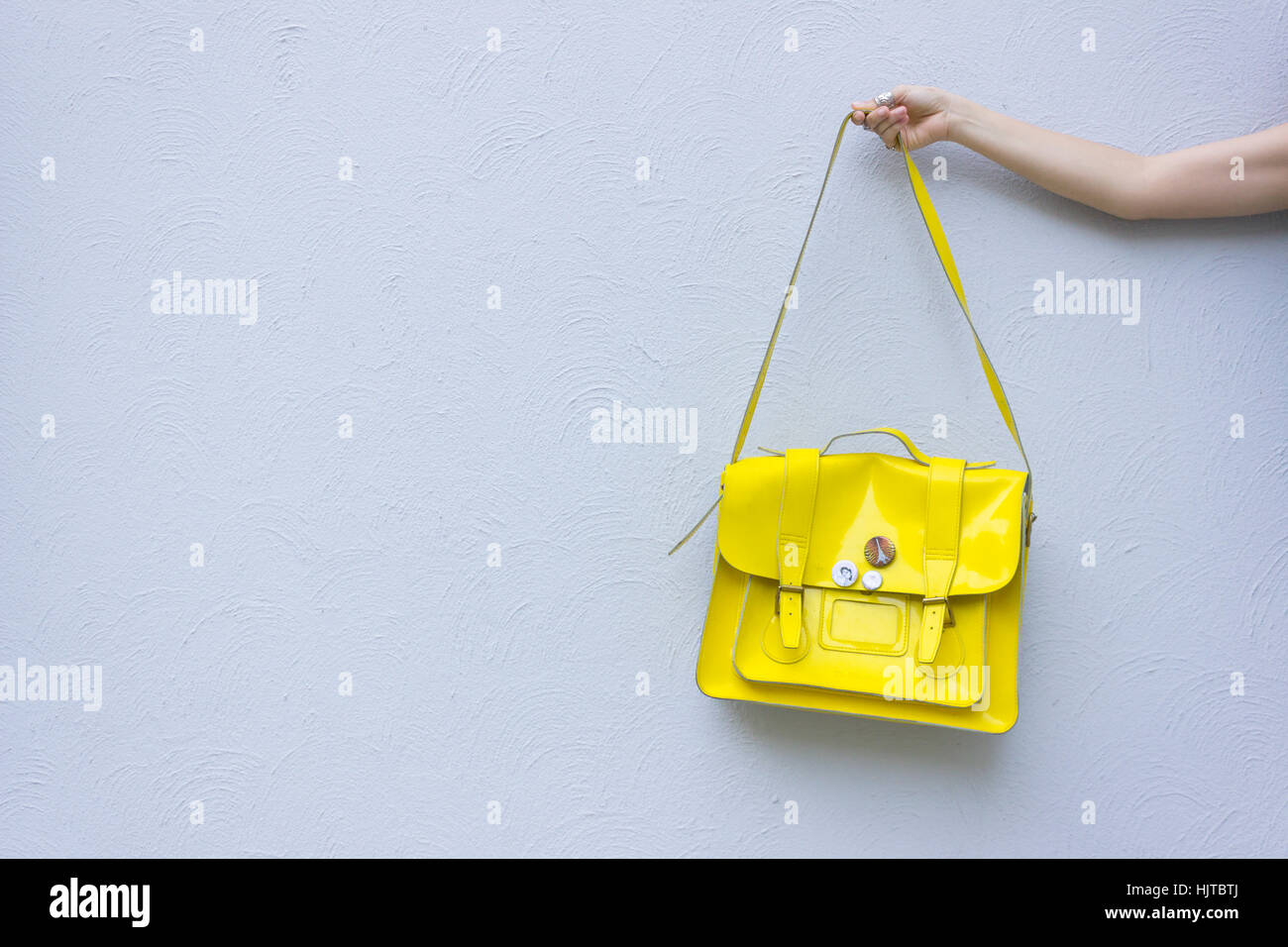 Giovani caucasici azienda femmina giallo borsa contro il grigio parete testurizzata Foto Stock