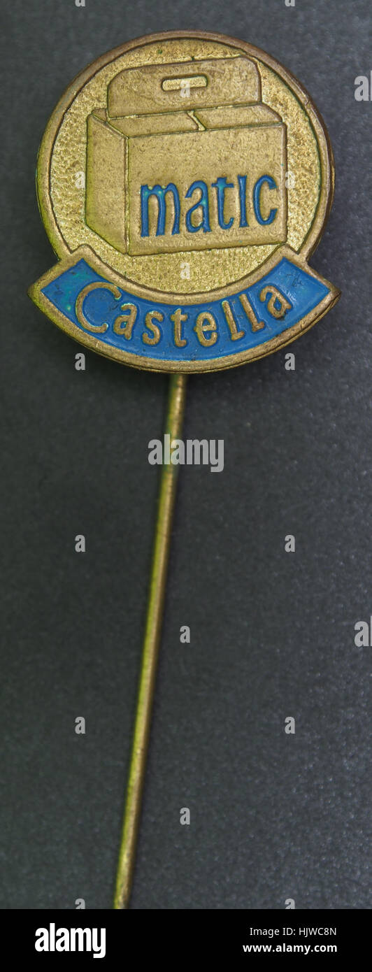 La Castella Matic speldje è una spilla pubblicitaria vintage del marchio Castella, tipicamente utilizzata nelle campagne promozionali durante la metà del XX secolo. La Castella Matic era nota per i suoi prodotti innovativi nell'industria alimentare. Foto Stock