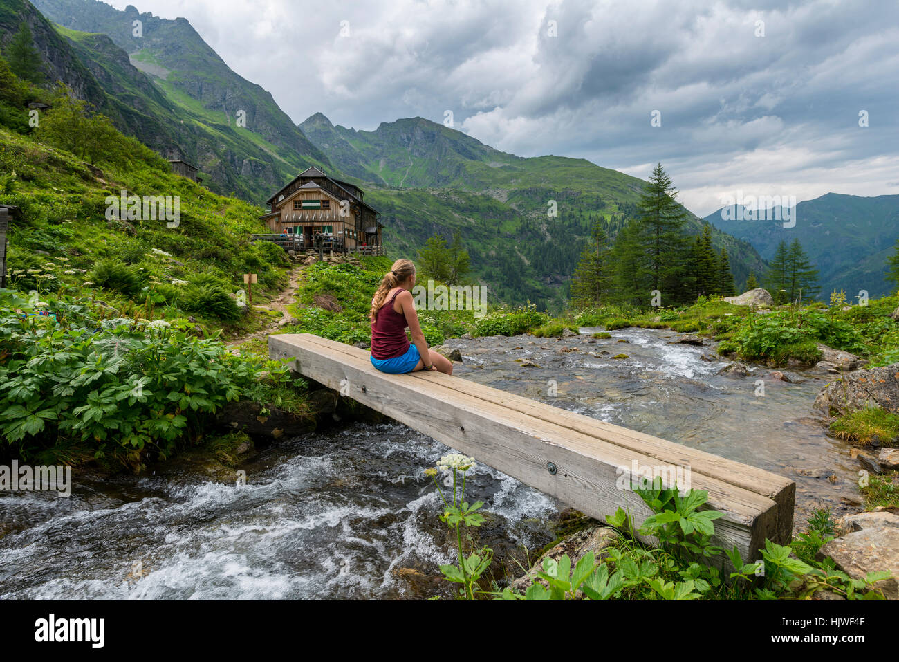 Escursionista sul ponte di legno attraverso torrente di montagna, Golling capanna, Rohrmoos-Untertal, Schladminger Tauern, Stiria, Austria Foto Stock