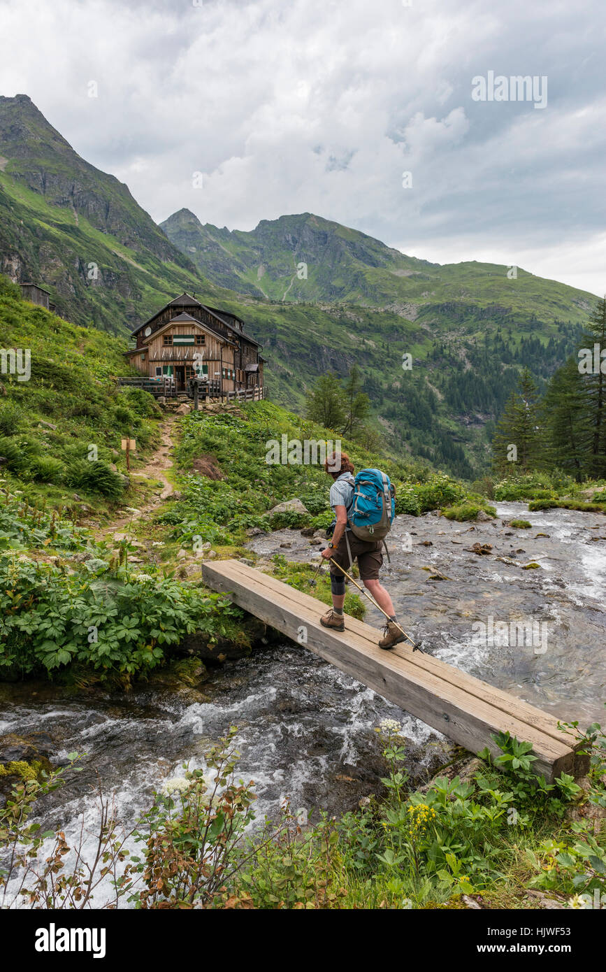 Escursionista attraversa il ponte di legno attraverso torrente di montagna, Golling capanna, Rohrmoos-Untertal, Schladminger Tauern, Stiria, Austria Foto Stock