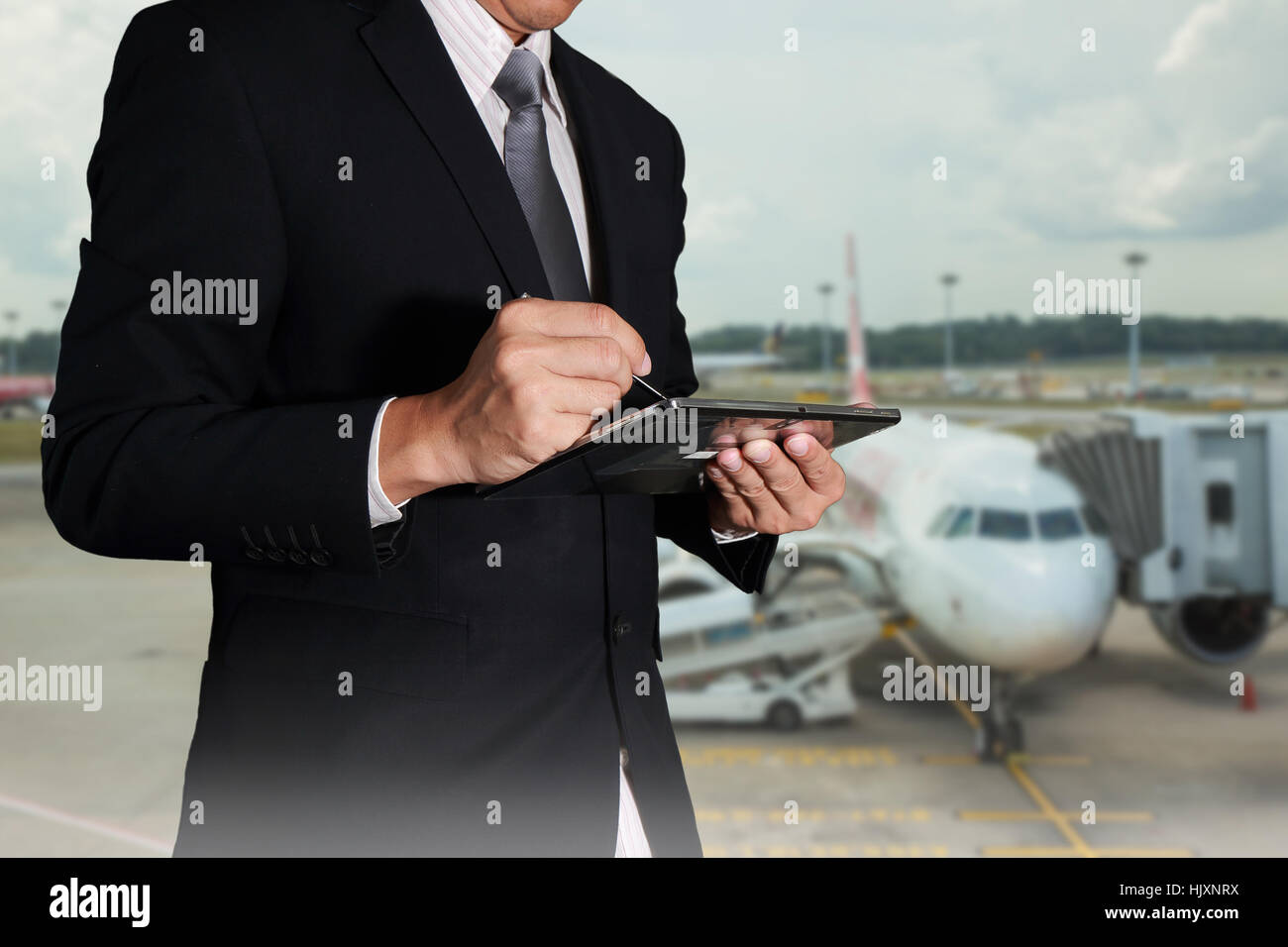 Uomo d'affari usando il tablet sul offuscata dall'aeroporto astratto come sfondo la comunicazione e il concetto di trasporto. Foto Stock