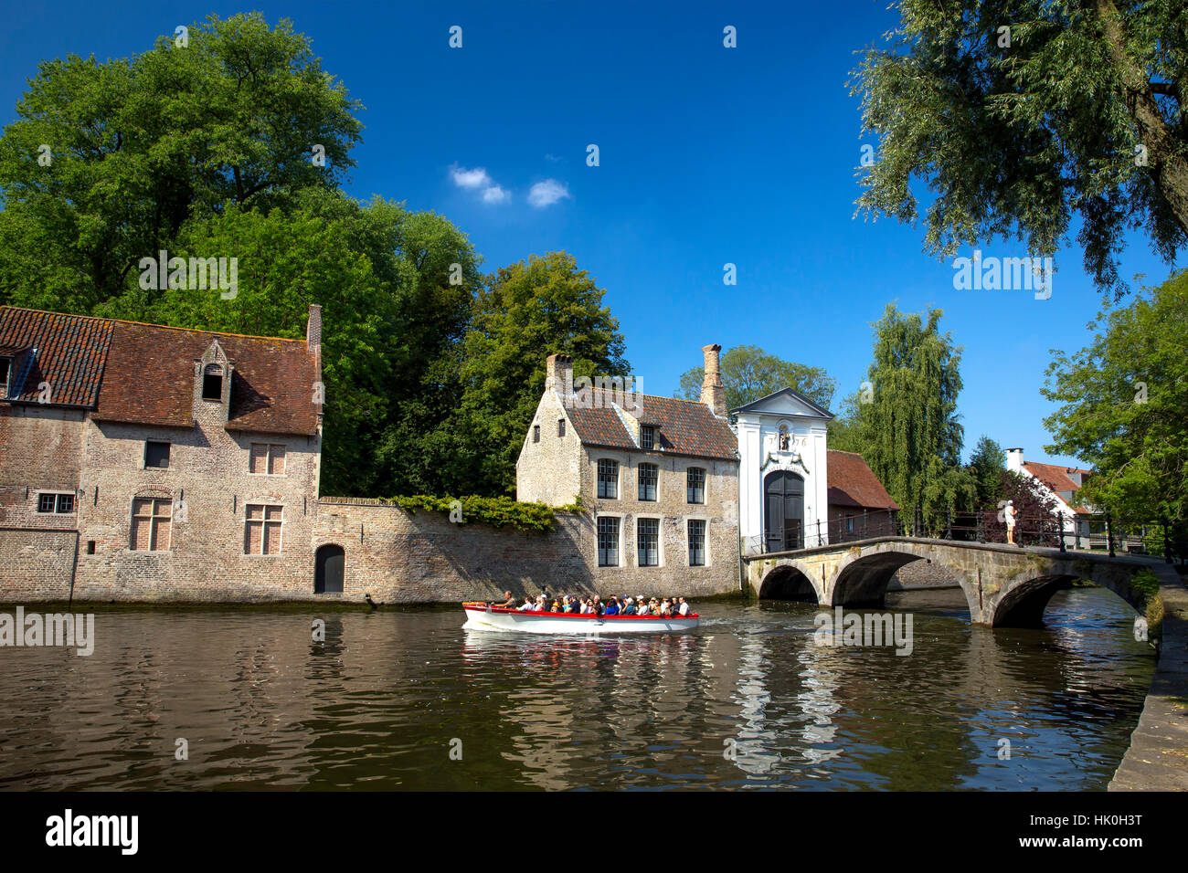 Imbarcazione turistica presso il lago Minnewater e Begijnhof ponte con ingresso al beghinaggio di Bruges, Belgio Foto Stock