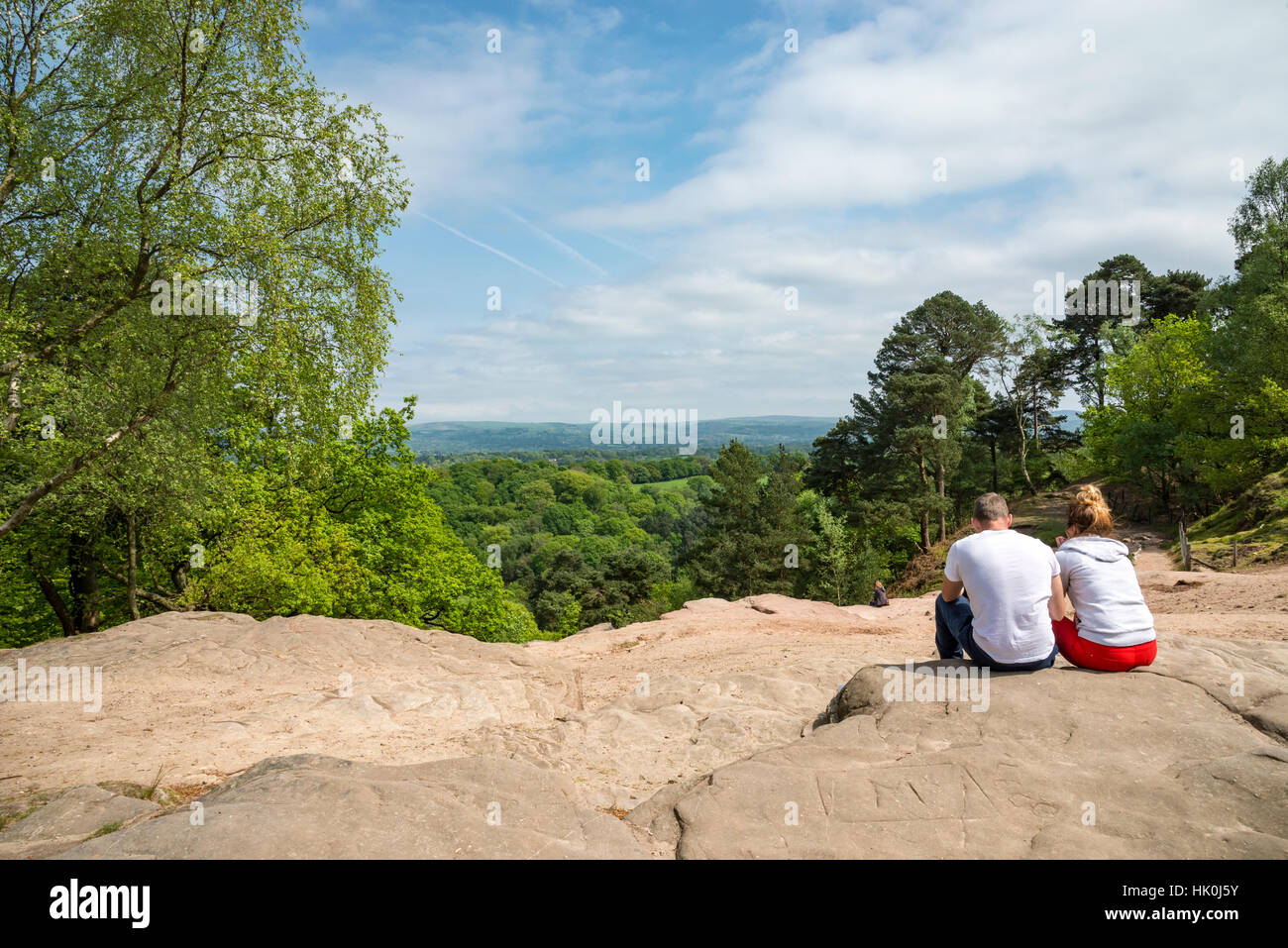 Coppia giovane seduto sulle rocce al punto tempestoso, Alderley Edge. Un ben noto punto di vista nella campagna del Cheshire. Foto Stock