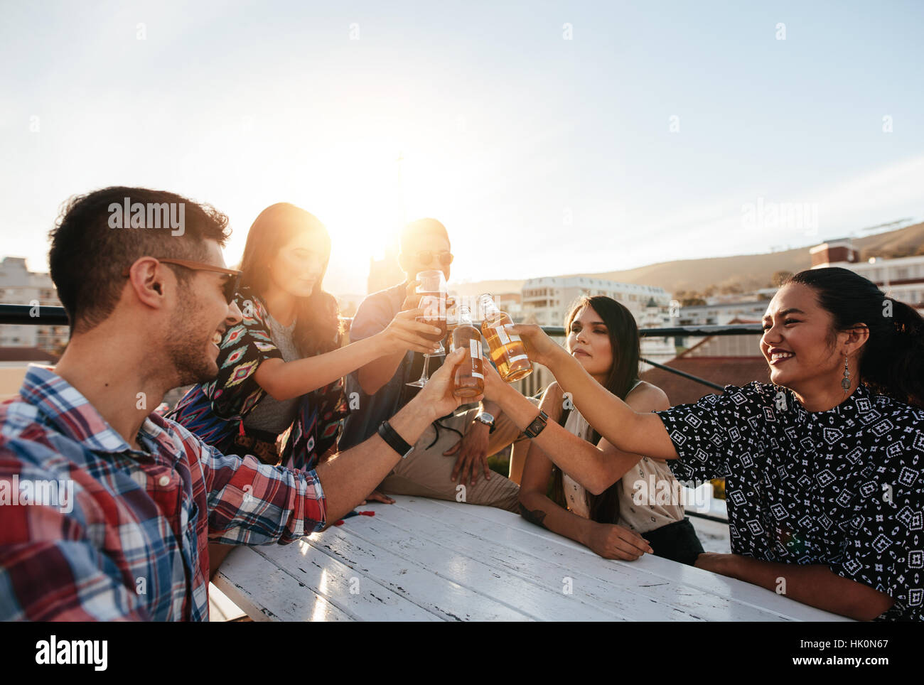 Un gruppo di giovani la tostatura bevande a parte sul tetto. Giovani amici godendo insieme con bevande. Foto Stock