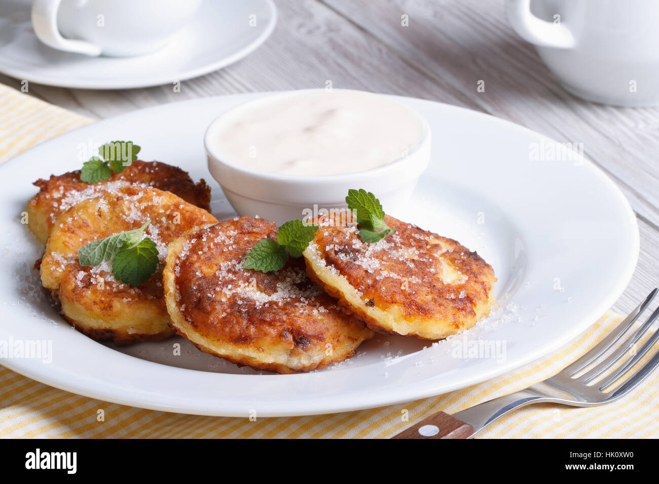 Porzione frittelle di formaggio su una piastra bianca con panna acida closeup orizzontale Foto Stock
