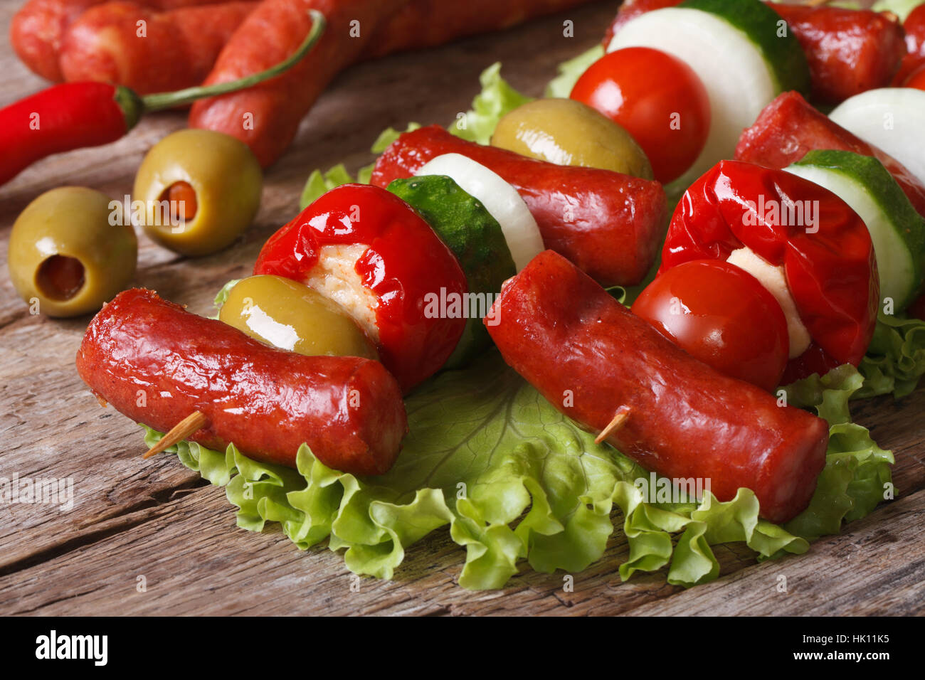 Salsicce alla griglia con pomodoro, olive, peperoncino, cipolle e cetrioli su spiedini closeup orizzontale Foto Stock