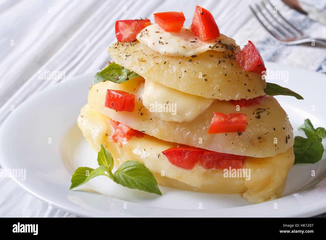 Patate novelle bollite con mozzarella, pomodoro e basilico su piastra bianca closeup orizzontale Foto Stock