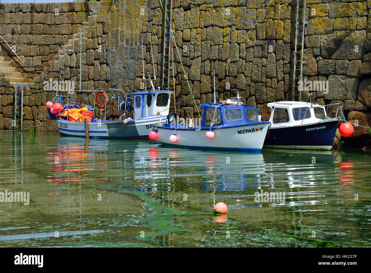 Piccole barche da pesca ormeggiate contro la parete del porto nel pittoresco villaggio di pescatori di Mousehole sulla South Cornwall coast,Inghilterra, Gran Bretagna Foto Stock