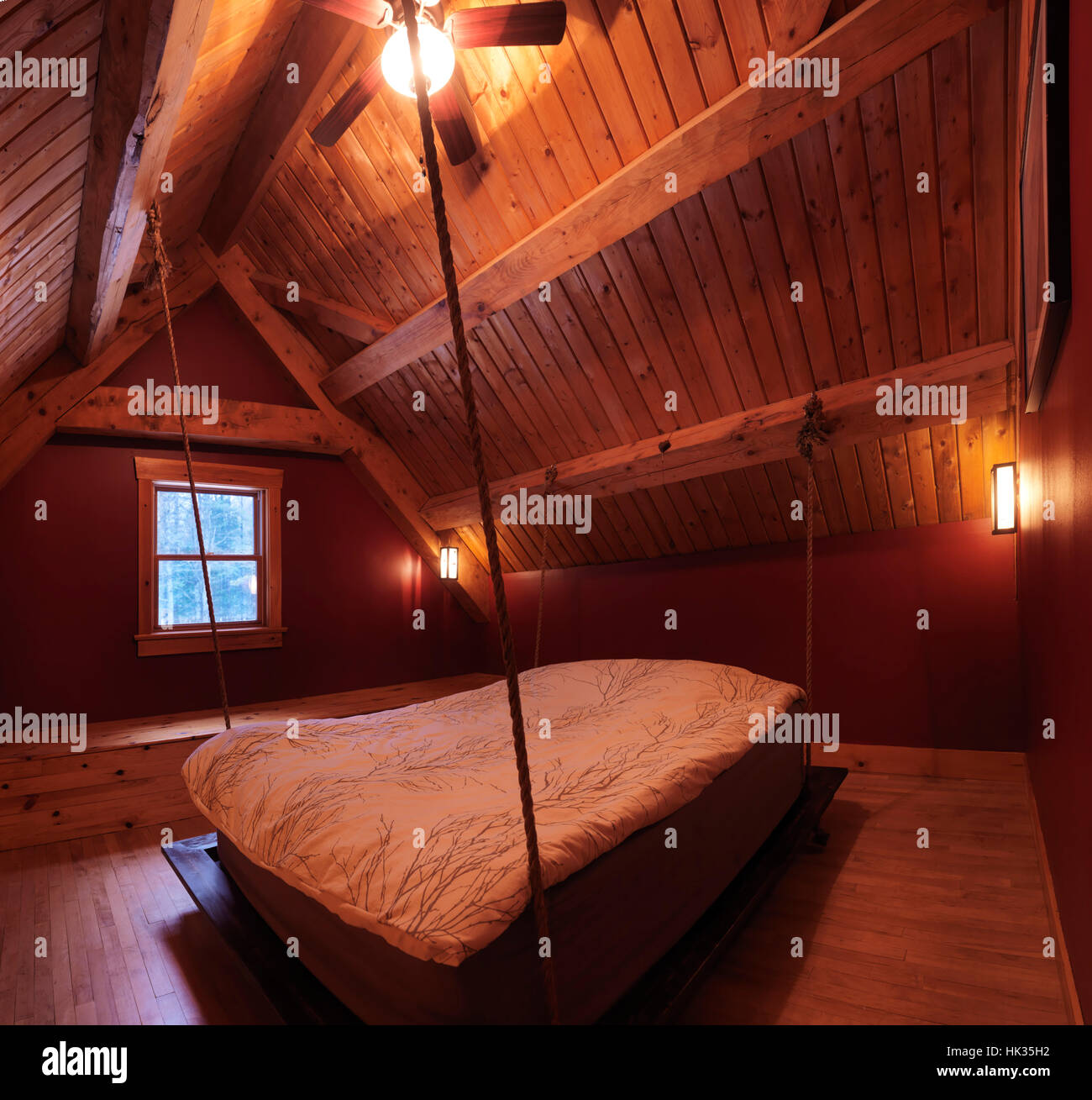 Attico mansarda camera da letto con un letto sospeso in un canadese in legno a telaio country house, interno con un sacco di legno, Muskoka, Ontario, Canada Foto Stock