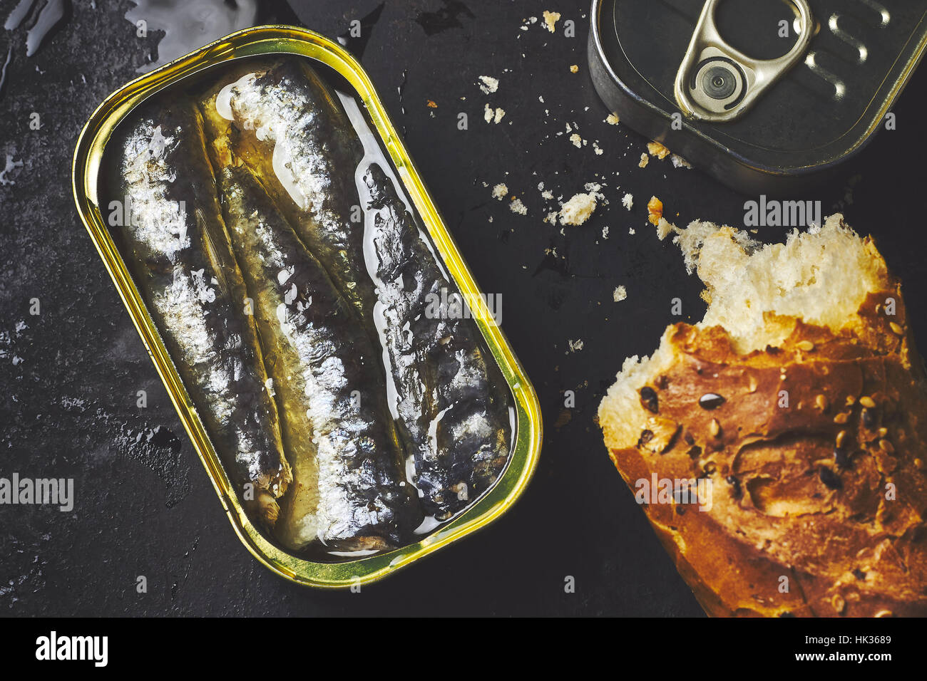 Sardine in un possibile con la pagnotta di pane nero su sfondo rustico. Vista superiore Foto Stock