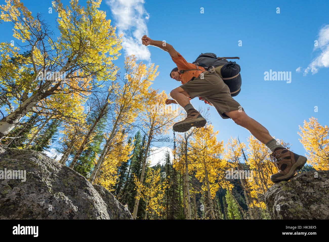 Backpacker saltando da boulder a boulder su un astragalo pendenza in Oregon Wallowa della montagna. Foto Stock