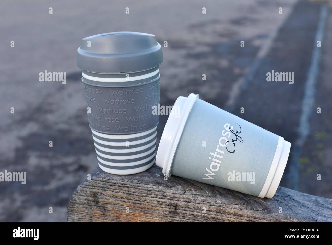 Waitrose monouso e riutilizzabili per tener lontano tazze da caffè o travell mug su una panchina nel parco, Central London, England, Regno Unito Foto Stock