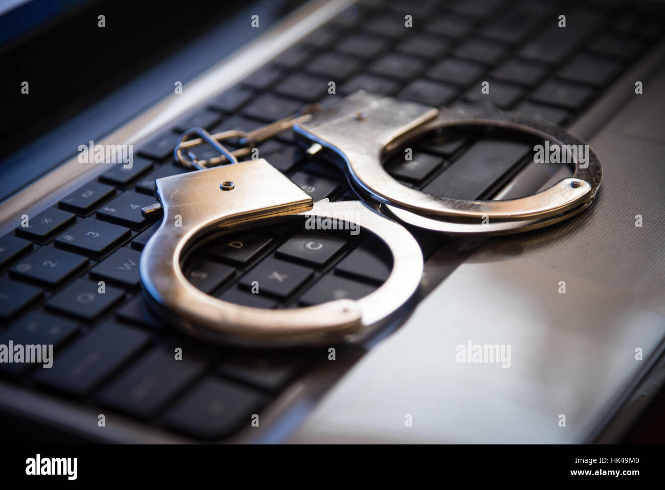 Messa a fuoco selettiva in manette su una tastiera cyber crime, hacking bullismo contro la nozione di diritto nel buio di basso tono tasto Foto Stock