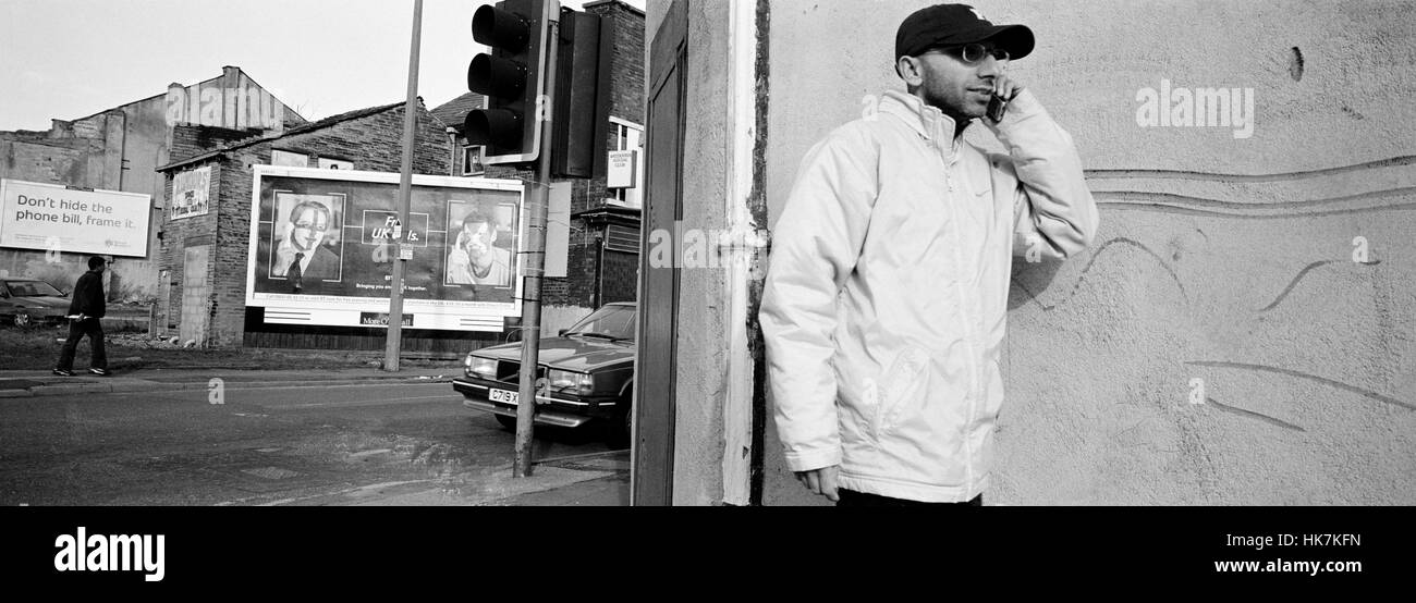Uomo asiatico sul telefono dopo i tumulti di Bradford. Manningham, Bradford Regno Unito. 9 Luglio 2001 Foto Stock