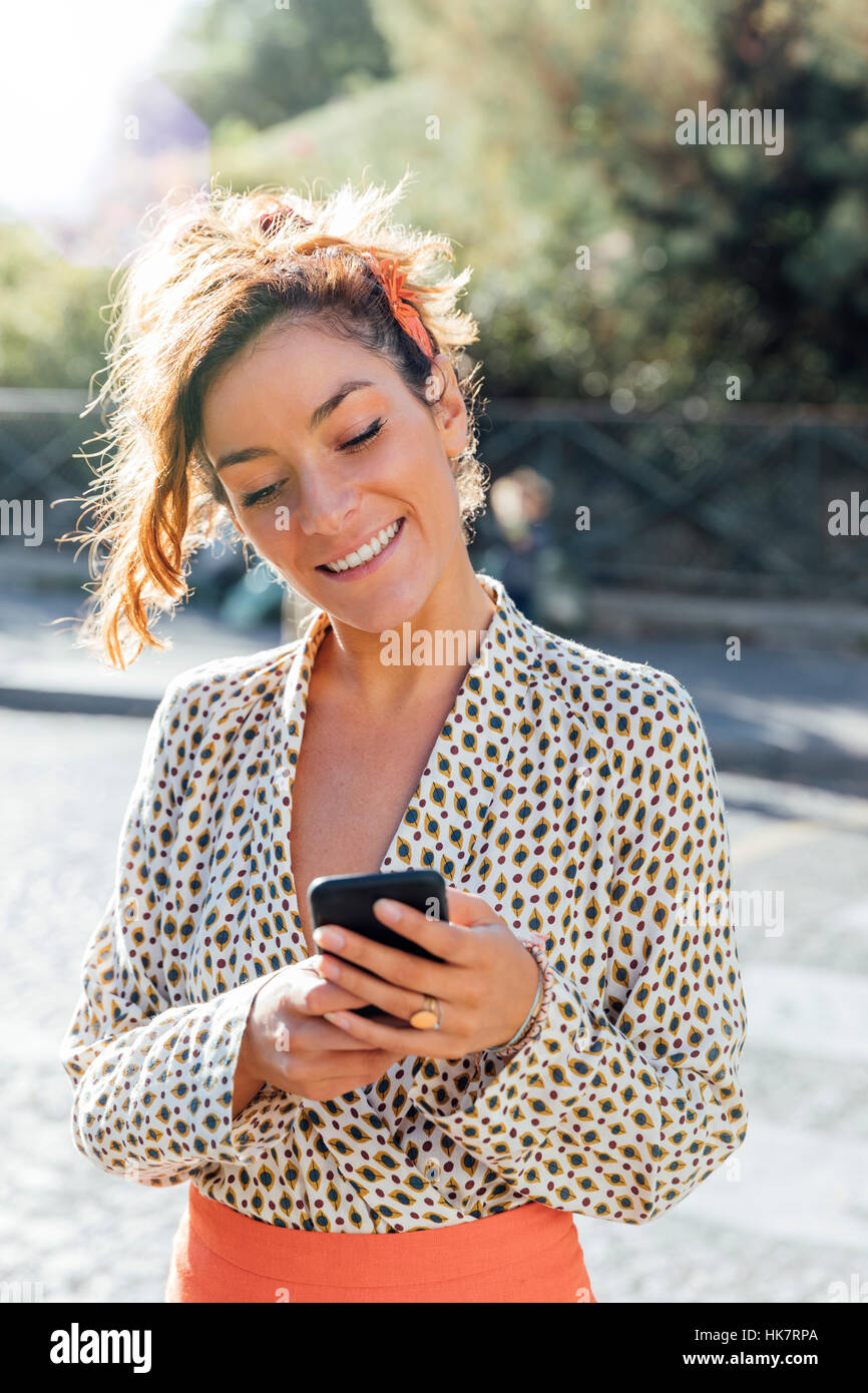 Parigi, donna attraente visitando il quartiere di Montmartre e utilizzando un telefono intelligente Foto Stock