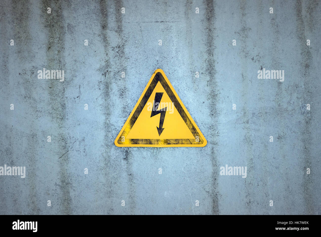 Elettricità segno di avvertimento su un sfondo spiovente Foto Stock