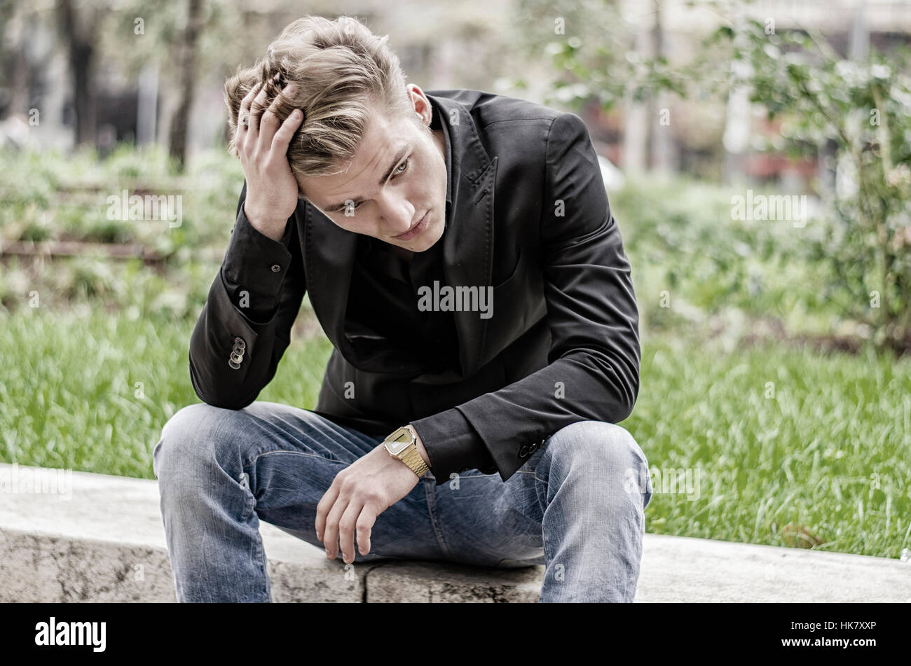 Premuto bianco giovane uomo seduto al lato della strada Foto Stock