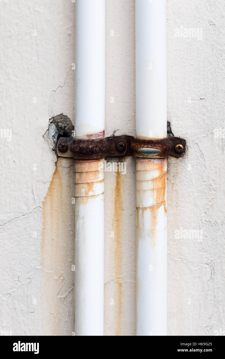 Bianco sporco tubo con la fascetta arrugginito sulla parete del settore. Foto Stock