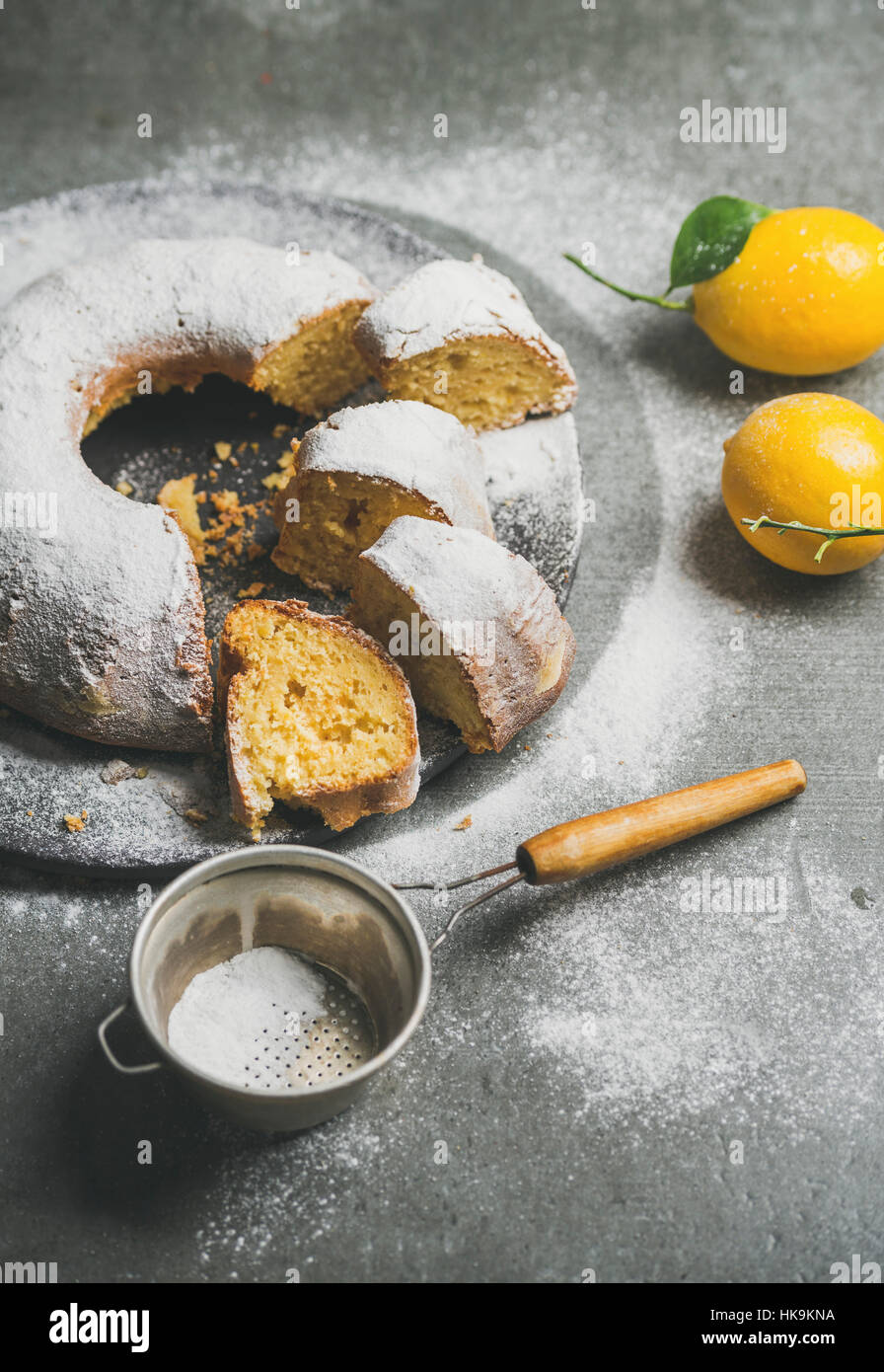 In casa senza glutine bundt di limone la torta con lo zucchero in polvere sul cemento grigio sfondo, il fuoco selettivo Foto Stock