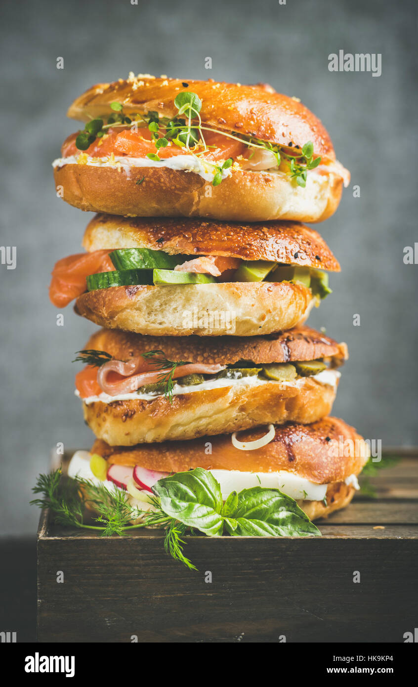 Cumulo di bagel con salmone, uova, verdure, capperi e crema di formaggio, di cemento grigio Sfondo. Una sana prima colazione, pranzo o take-away concetto alimentare Foto Stock